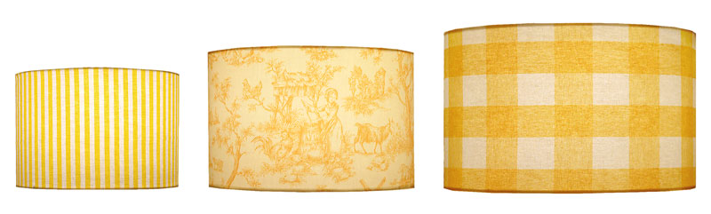 Different sizes of cylinder shape lampshades in stripe, toile and check fabric print designs in a variety of yellow colors.