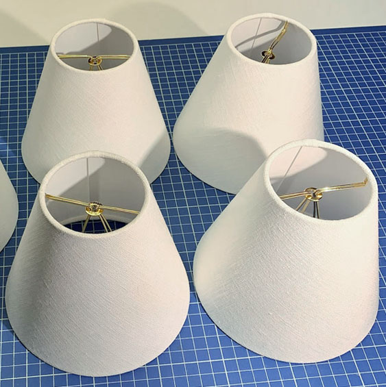 Small lampshades with flame clip fitters in white linen for chandeliers or sconces.